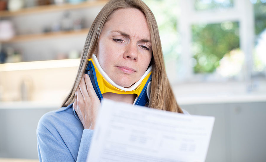 A woman with a neck injury reading legal; documents in her home​