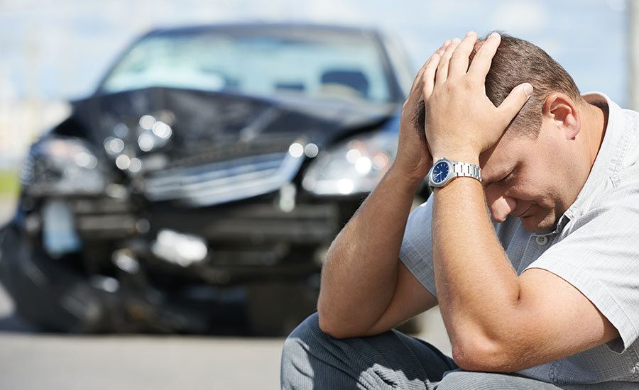 An upset man in front of a crashed car​