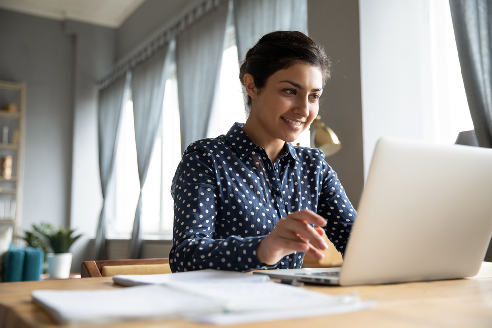 A smiling woman reading from laptop