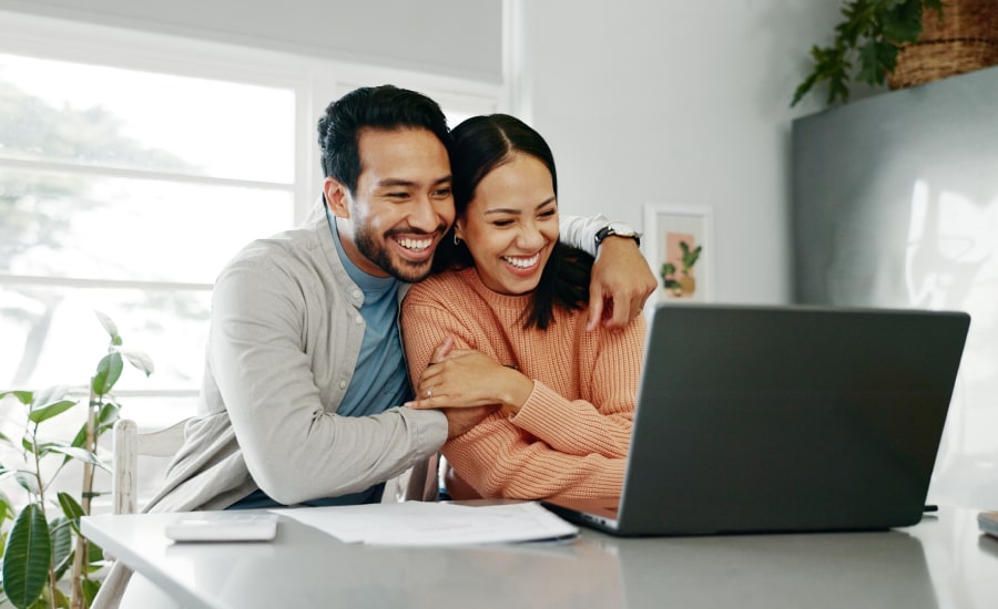 A happy couple looking at a laptop​