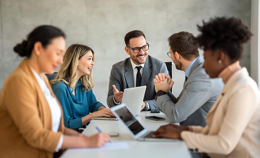 A smiling manager at a meeting with his team